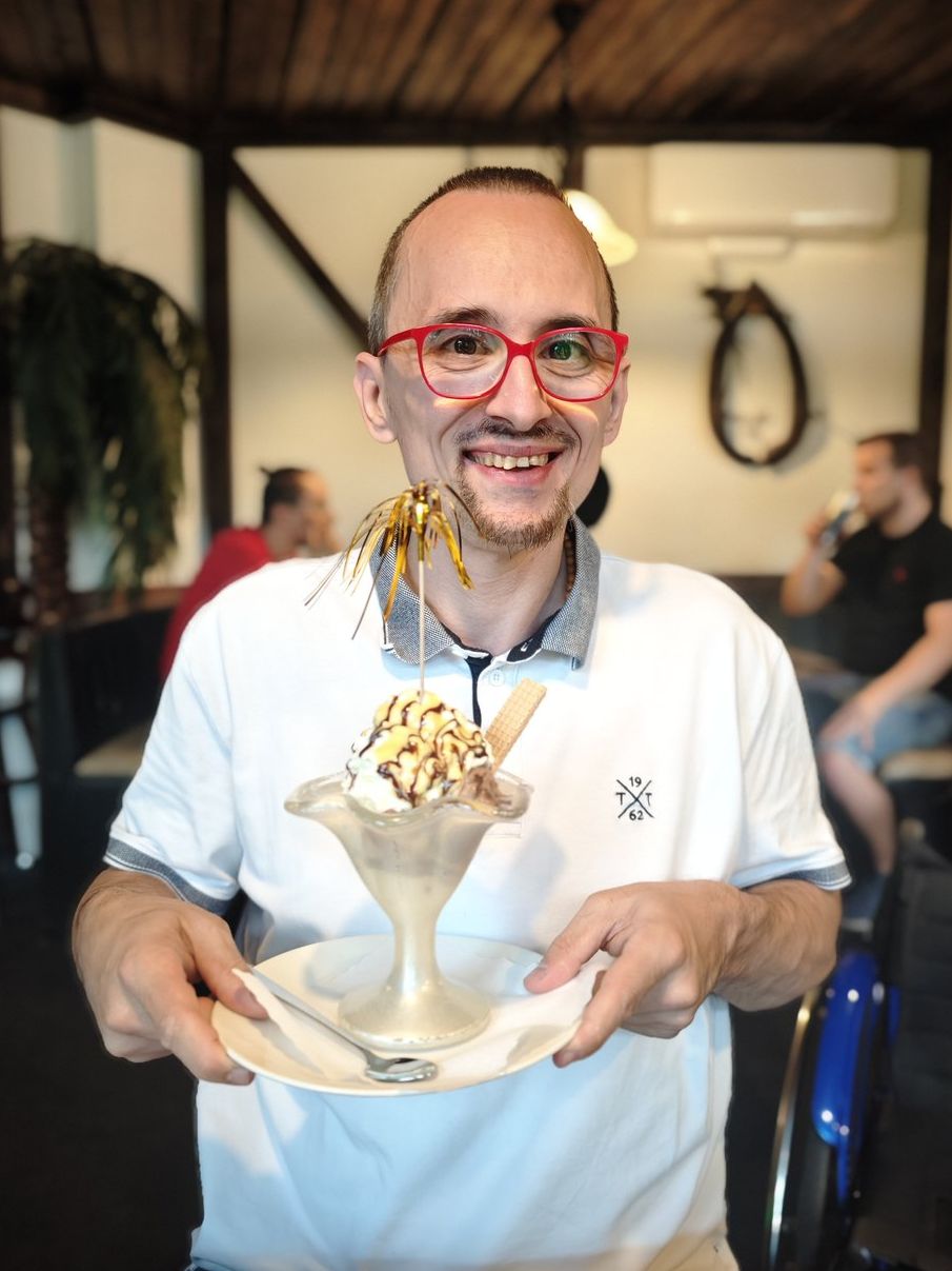 Erwin Strobl hält lachend einen großen Eisbecher in den Händen