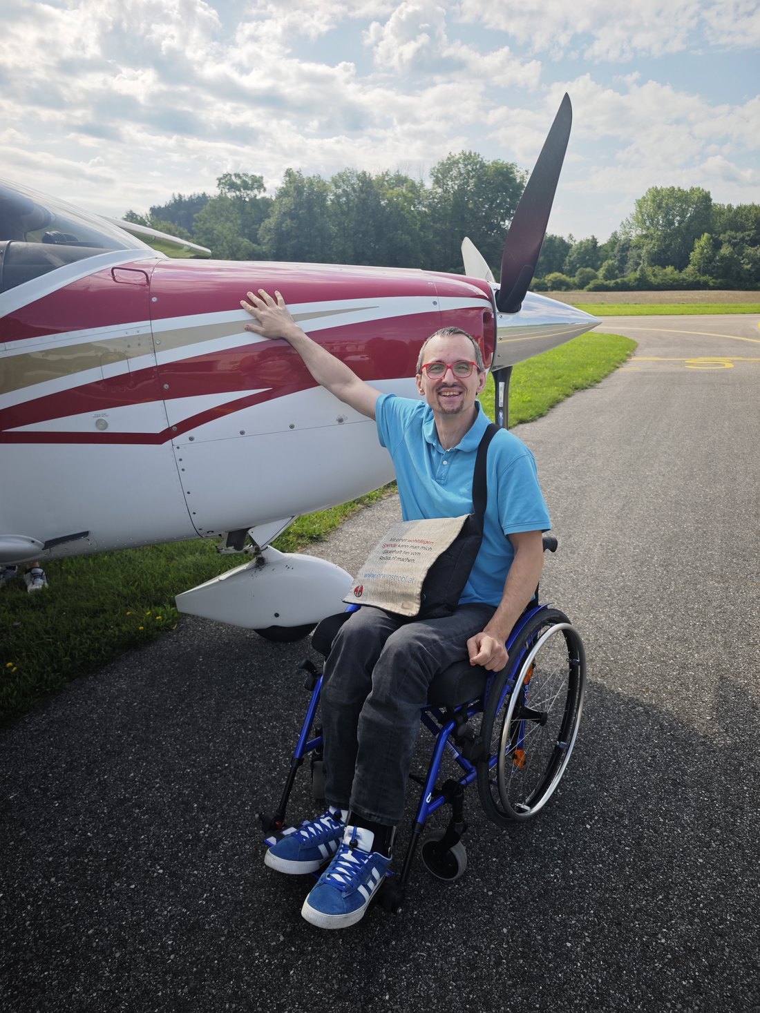 Erwin Strobl im Rollstuhl neben einem kleinen Flugzeug auf dem Flugplatz
