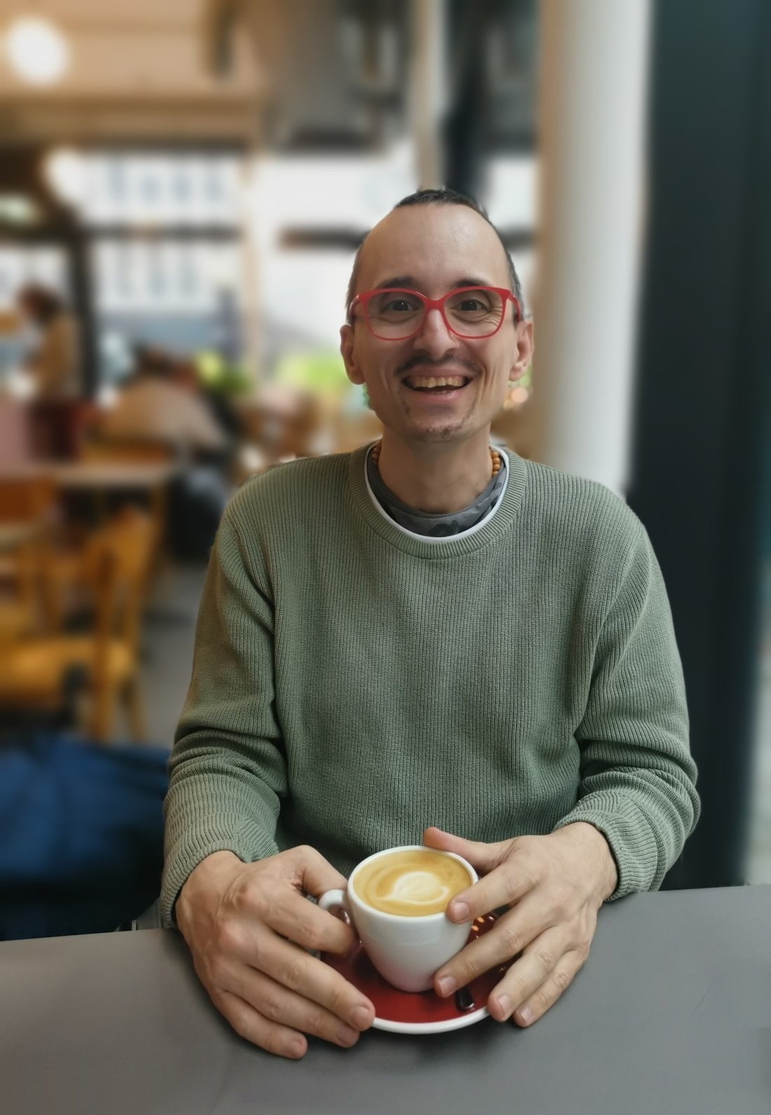 Erwin Strobl sitzt lächelnd mit einer Tasse Kaffee in einem Café